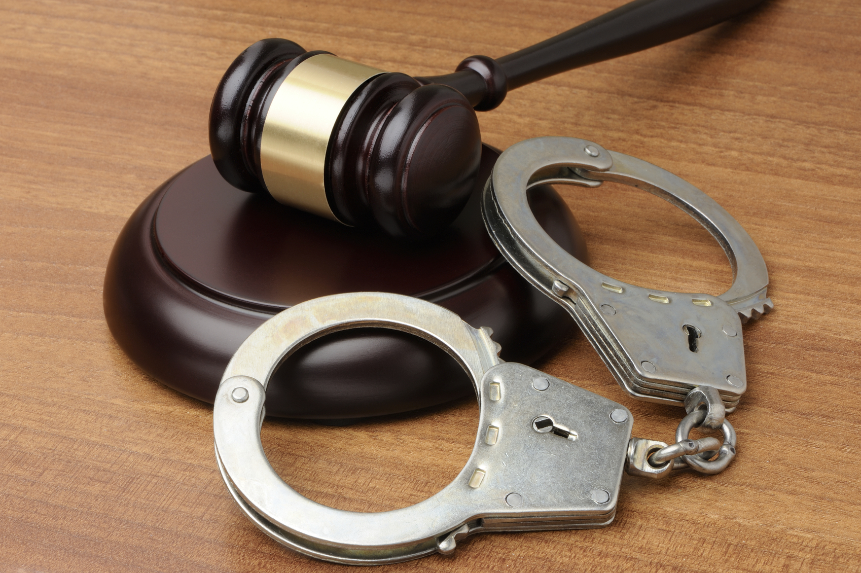 Handcuffs with gavel on a wood background